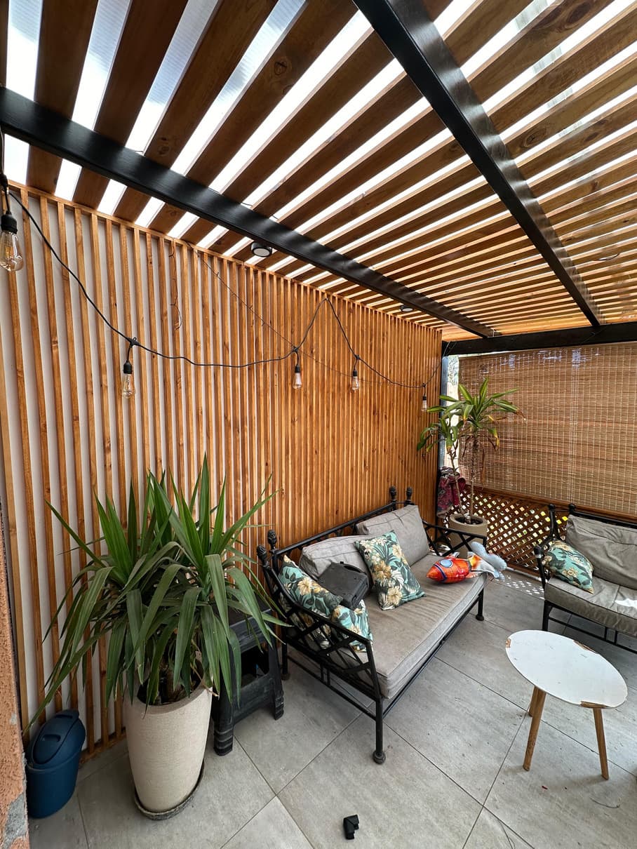 Estar exterior con muro revestido en madera.